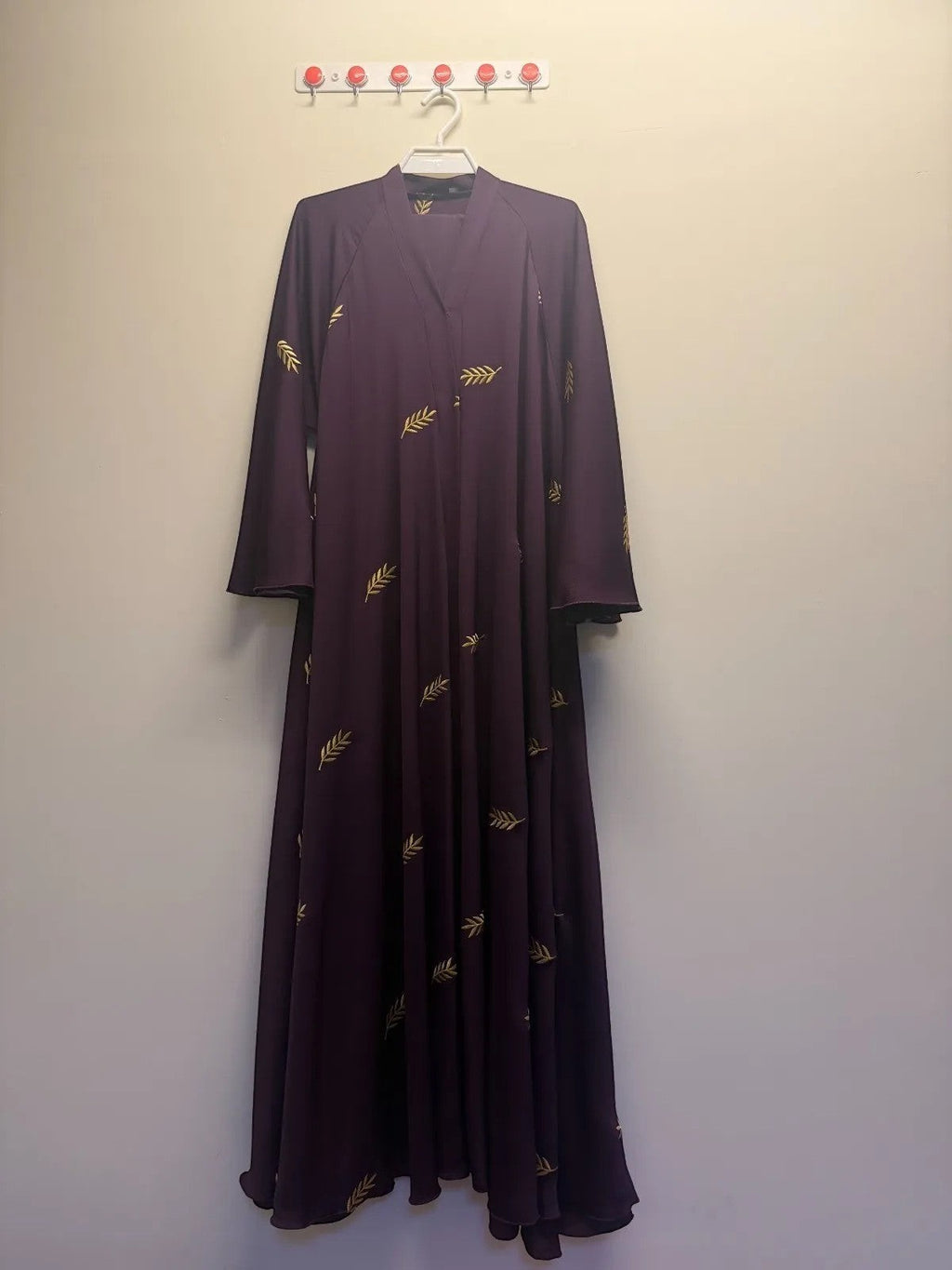 A&M FANCY STORE plum abaya with gold leaf embroidery, V-neck, and wide sleeves.