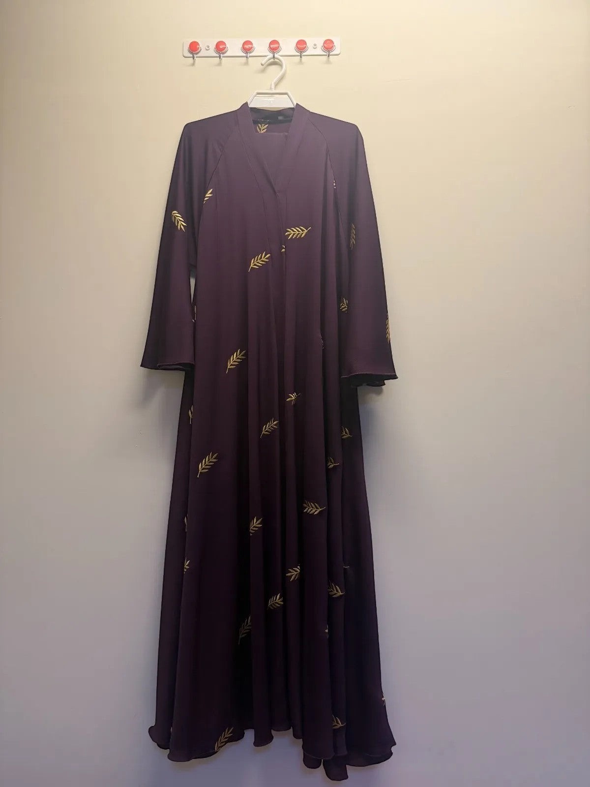 A&M FANCY STORE plum abaya with gold leaf embroidery, V-neck, and wide sleeves.